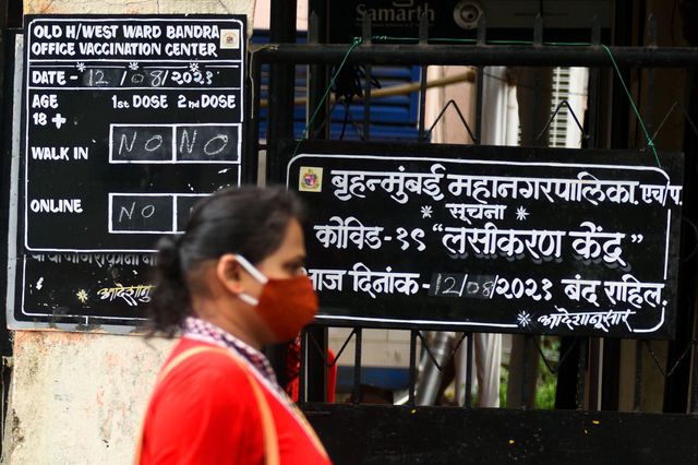 A woman walks past the entrance of a COVID-19 vaccination center in Mumbai, India that has been shut due to a supply shortage of supplies, August 12th, 2021.